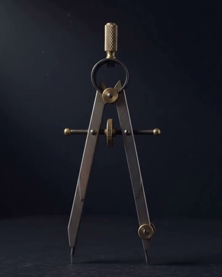 Vintage drafting compass standing open on its points on a dark ground